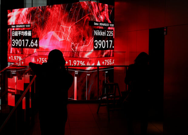 Visitors watch electronic screens displaying Japan's Nikkei share average, which surged past an all-time record high scaled in December 1989, inside a building in Tokyo
