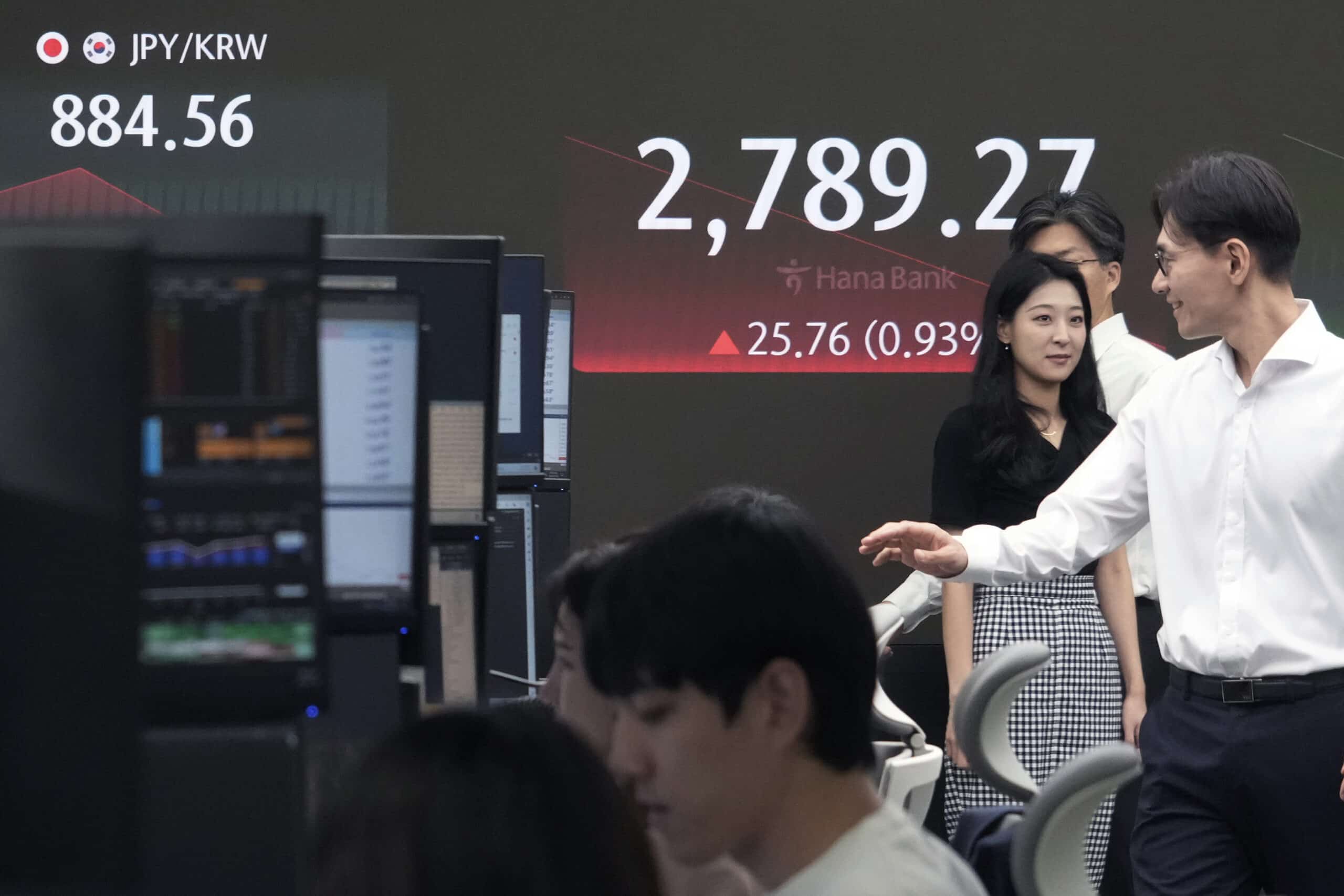 Currency traders pass by the screen showing the Korea Composite Stock Price Index (KOSPI) at the foreign exchange dealing room of the KEB Hana Bank headquarters in Seoul, South Korea, Tuesday, July 23, 2024. 