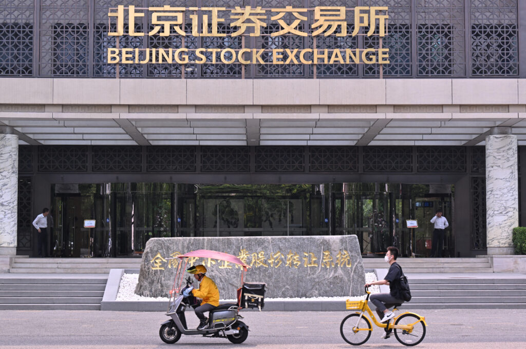 People ride vehicles past the Beijing Stock Exchange in Beijing on July 9, 2024. 
