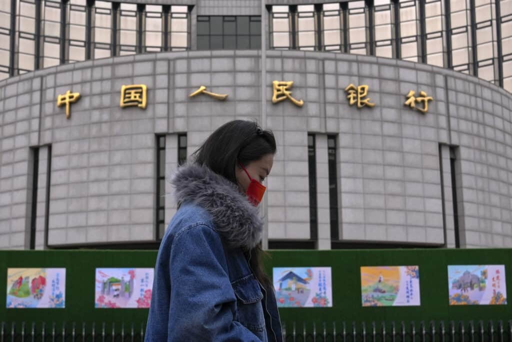 A woman walks by China's central bank, or the People's Bank of China in Beijing, Tuesday, Feb. 20, 2024.