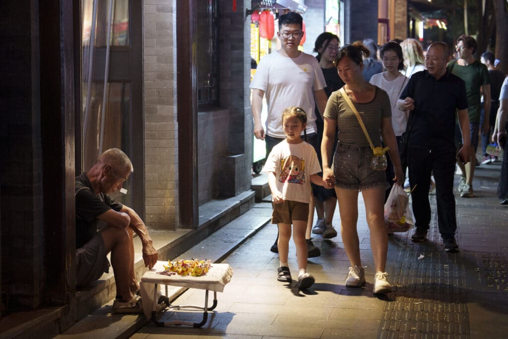 A Chinese man sits outside a store trying to sell his handcrafted souvenir in downtown Beijing, Friday, July, 26, 2024.