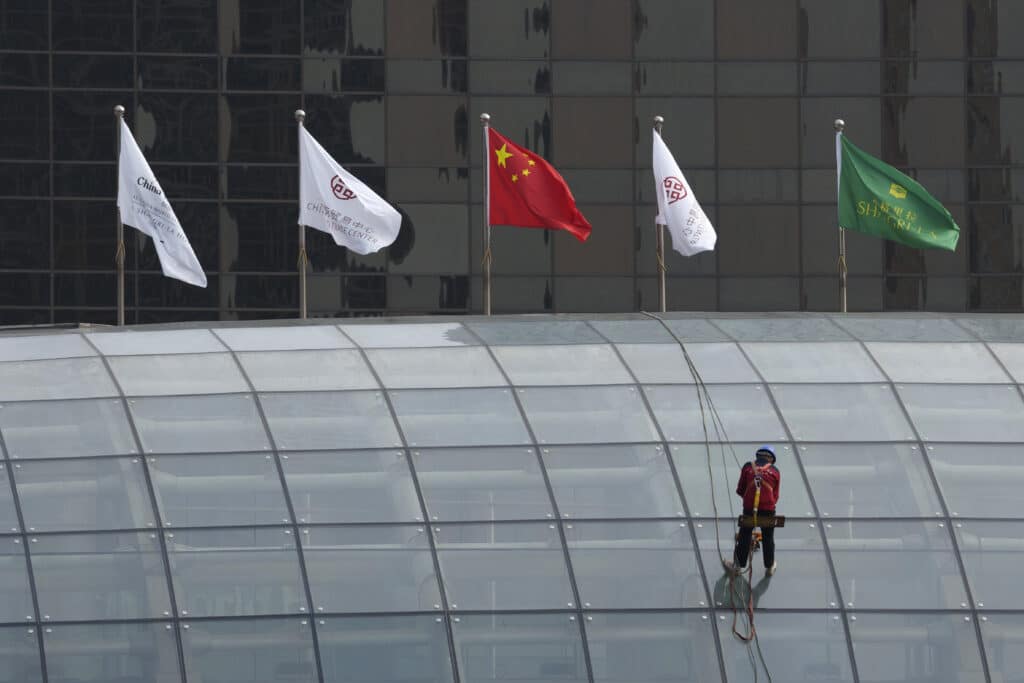 A worker descends on the rooftop of a building at the central business district in Beijing, China, Monday, July 15, 2024.