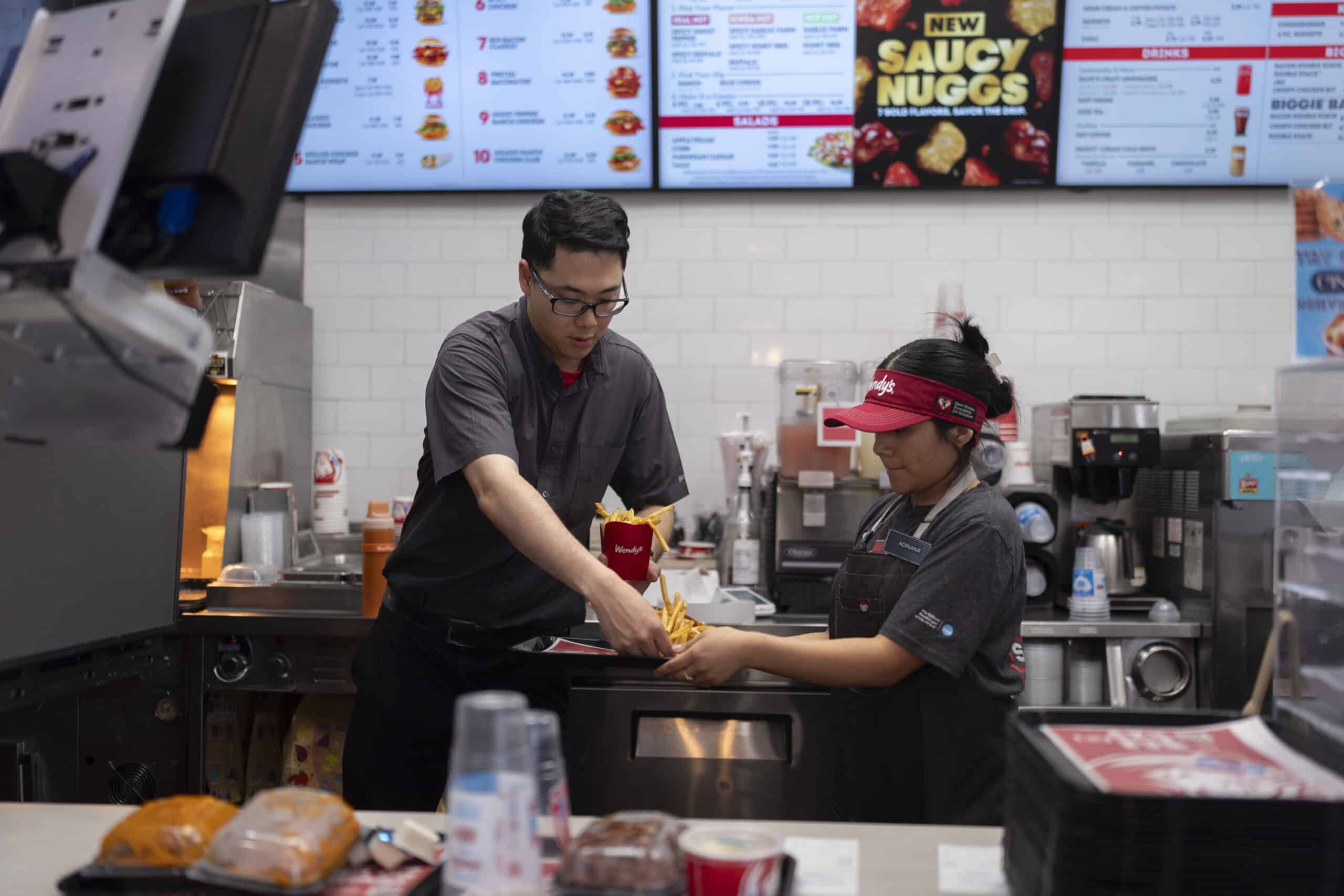 Lawrence Cheng, left, whose family owns seven Wendy's locations south of Los Angeles, works with part-time employee Adriana Ruiz at his Wendy's restaurant in Fountain Valley, Calif., June 20, 2024.