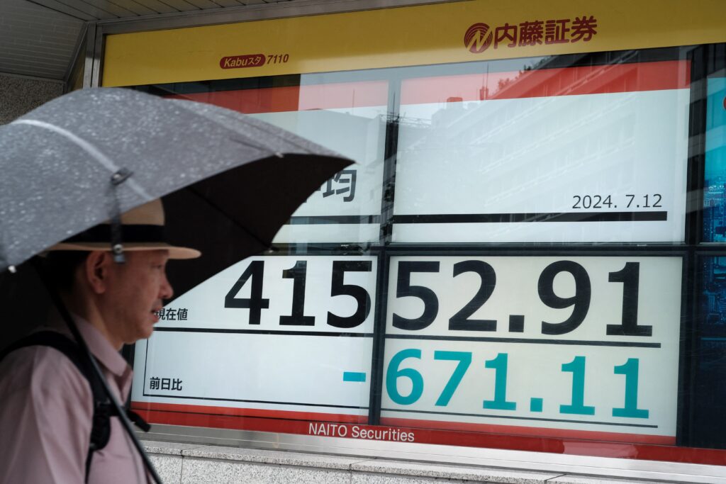 A man walks past an electronic board displaying the numbers of the Tokyo Stock Exchange share price in Tokyo on July 12, 2024.