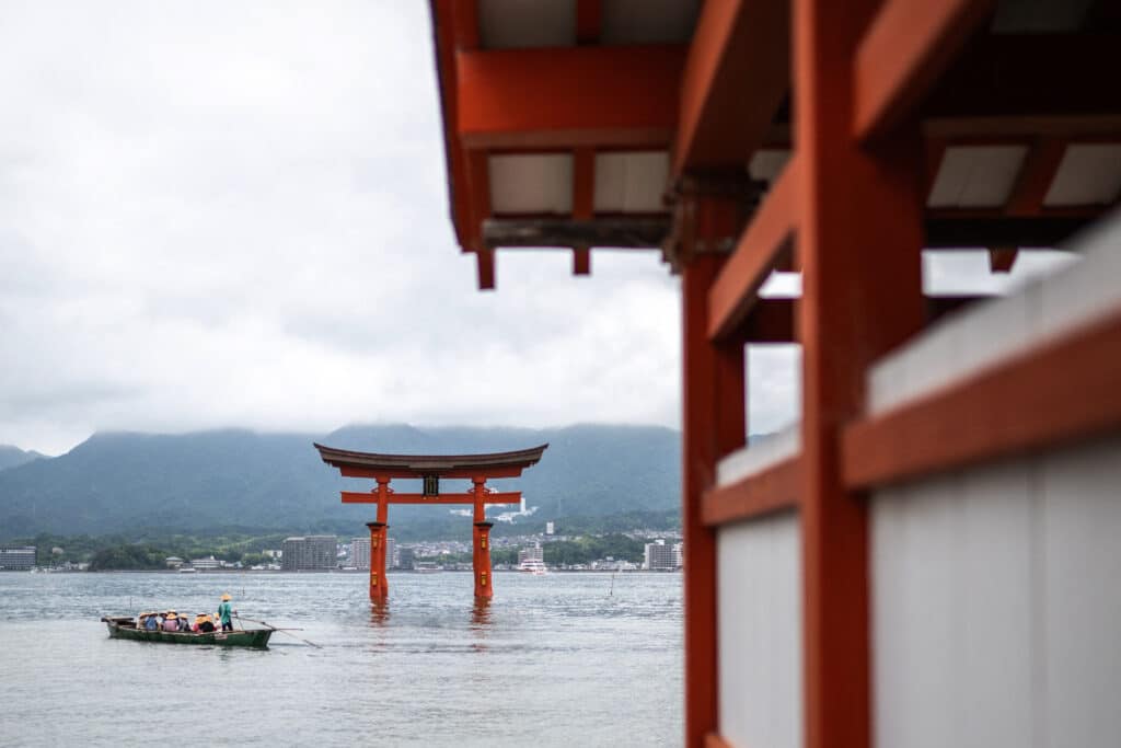 Tourists travel on a sightseeing boad sailing in front of the torii of Itsukushima Shrine (back), the popular tourist destination of Miyajima island in Hiroshima Prefecture on June 10, 2024.