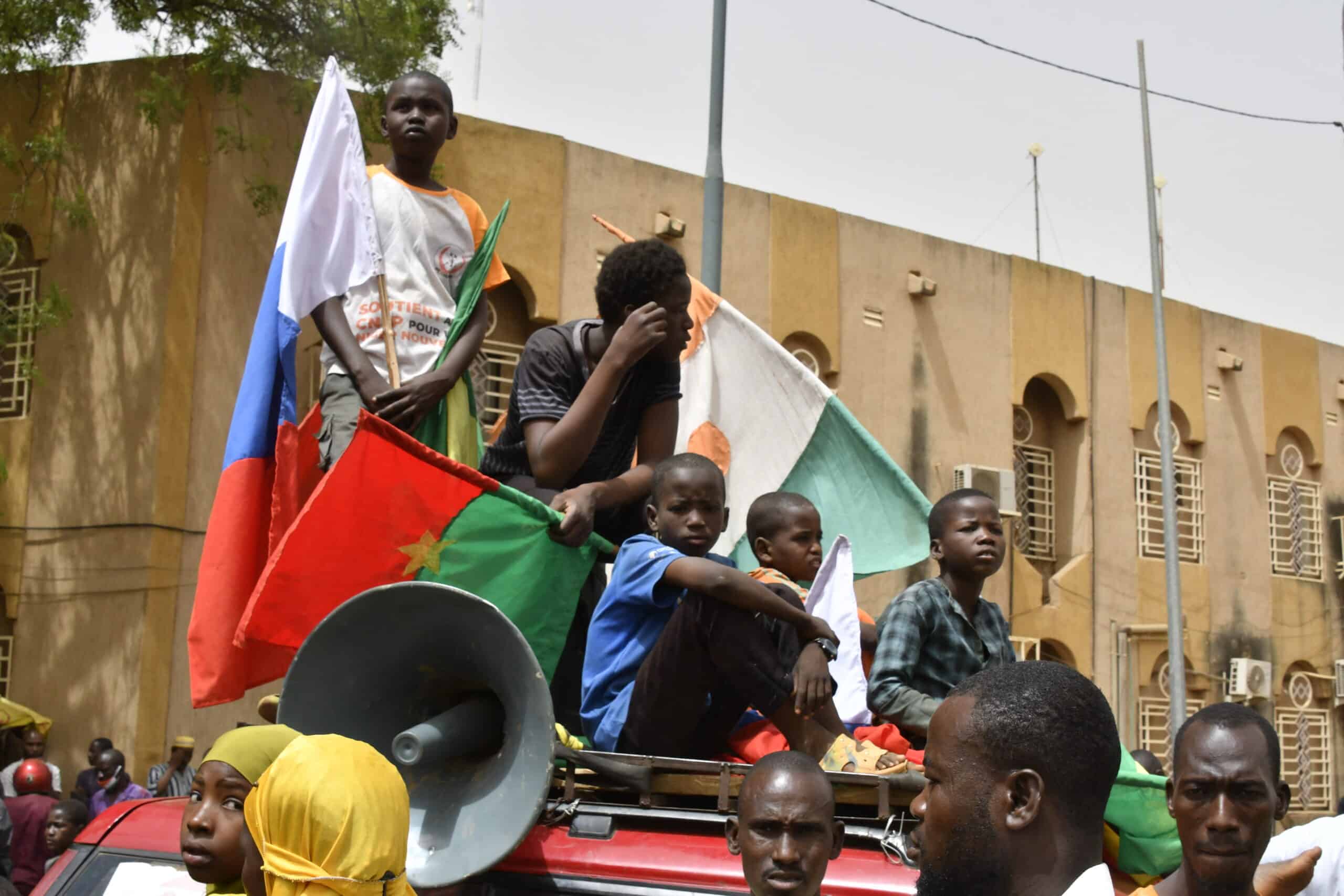 Young boys gather on top of a car while displaying flags of Niger, Burkina Faso and Russia during a demonstration for the immediate departure of United States Army soldiers deployed in northern Niger in Niamey, on April 13, 2024. 