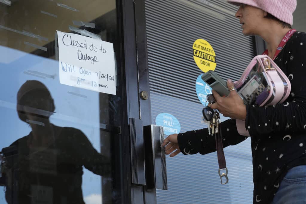 Danielle Tuttle tries the door to a department of motor vehicles location to find it locked and the location closed due to an outage Friday, July 19, 2024, in St. Louis.