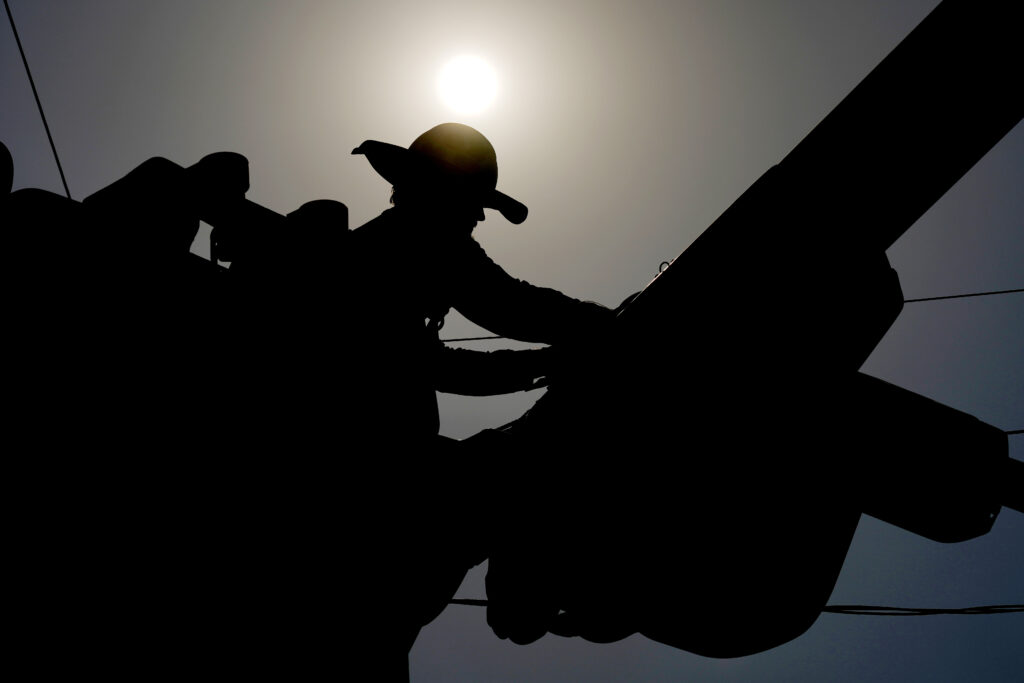 FILE - A linesman works on power lines under the morning sun, July 12, 2024, in Phoenix. On Wednesday, July 31, 2024.