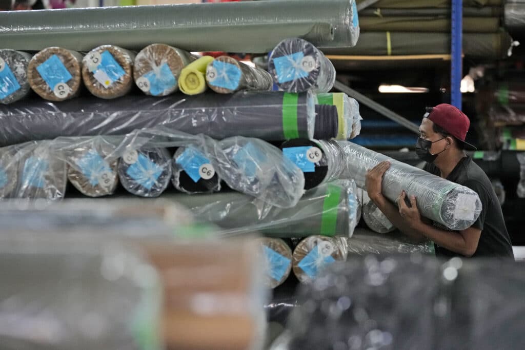 A worker arranges fabric rolls at a factory belonging to PT Eksonindo Multi Product Industry