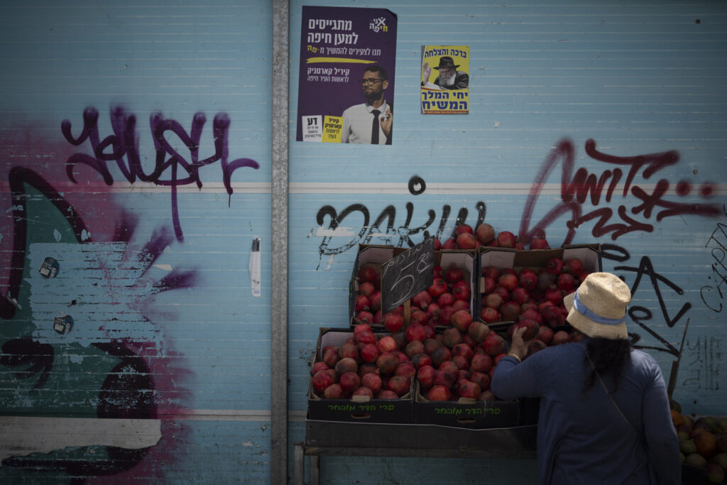 A woman checks the pomegranates displayed at a street market in Haifa, Israel, Friday, Aug. 16, 2024.