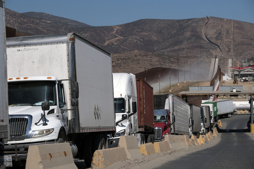 Trucks queue next to the US-Mexico border to cross to the United States at the Otay crossing port in Tijuana, Baja California State, Mexico, on August 22, 2024. 