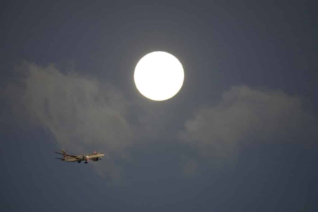 Isang Qatar Airways jetliner ang paparating para lumapag sa Lisbon, na may supermoon sa background, sa pagsikat ng araw Martes, Ago. 20, 2024.