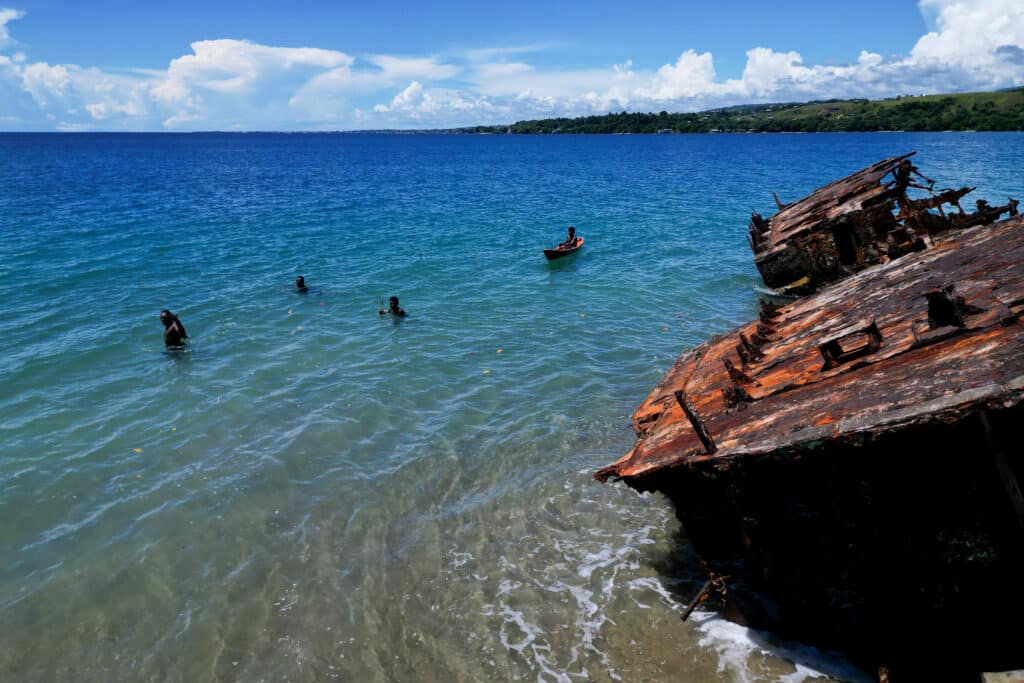 This picture taken on April 21, 2024 shows villagers next to a washed up shipwreck on the outskirts of Honiara, capital city of the Solomon Islands.