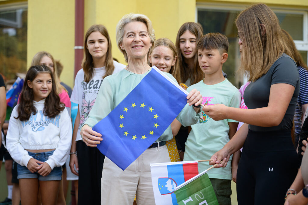 European Commission President, Ursula von der Leyen (C) holds a European flag 