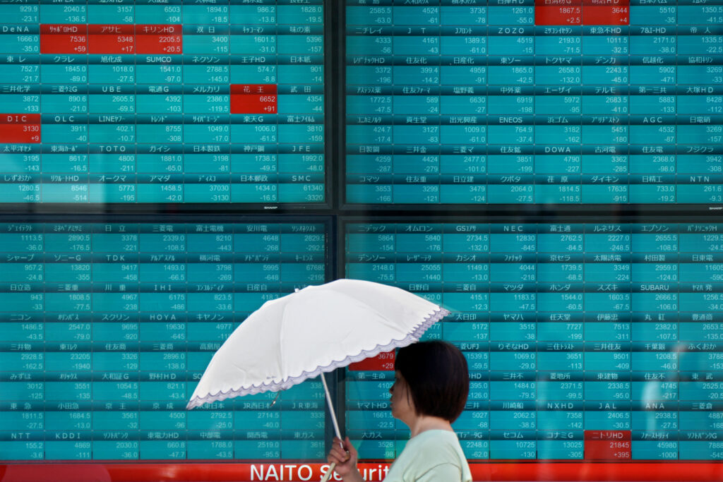 A woman walks in front of an electronic quotation board displaying stock prices of Nikkei 225 on the Tokyo Stock Exchange in Tokyo on September 4, 2024