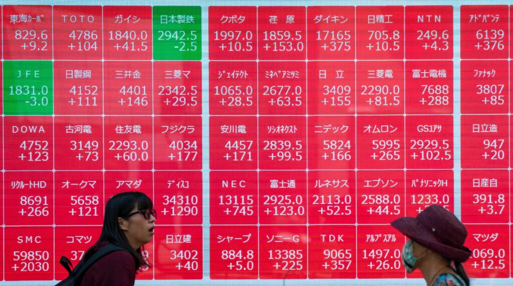 Pedestrians walk in front of an electronic quotation board displaying stock prices of Nikkei 225 on the Tokyo Stock Exchange in Tokyo on September 12, 2024. 