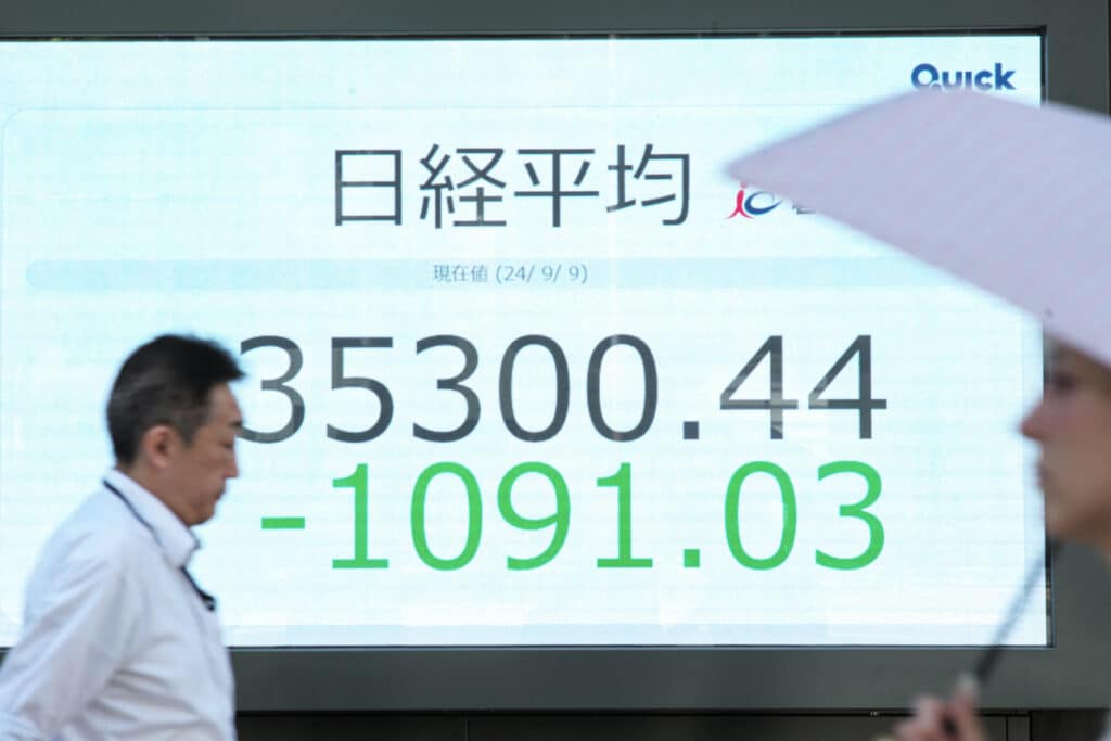 People walk in front of an electronic quotation board displaying the Nikkei index on the Tokyo Stock Exchange in Tokyo on September 9, 2024.