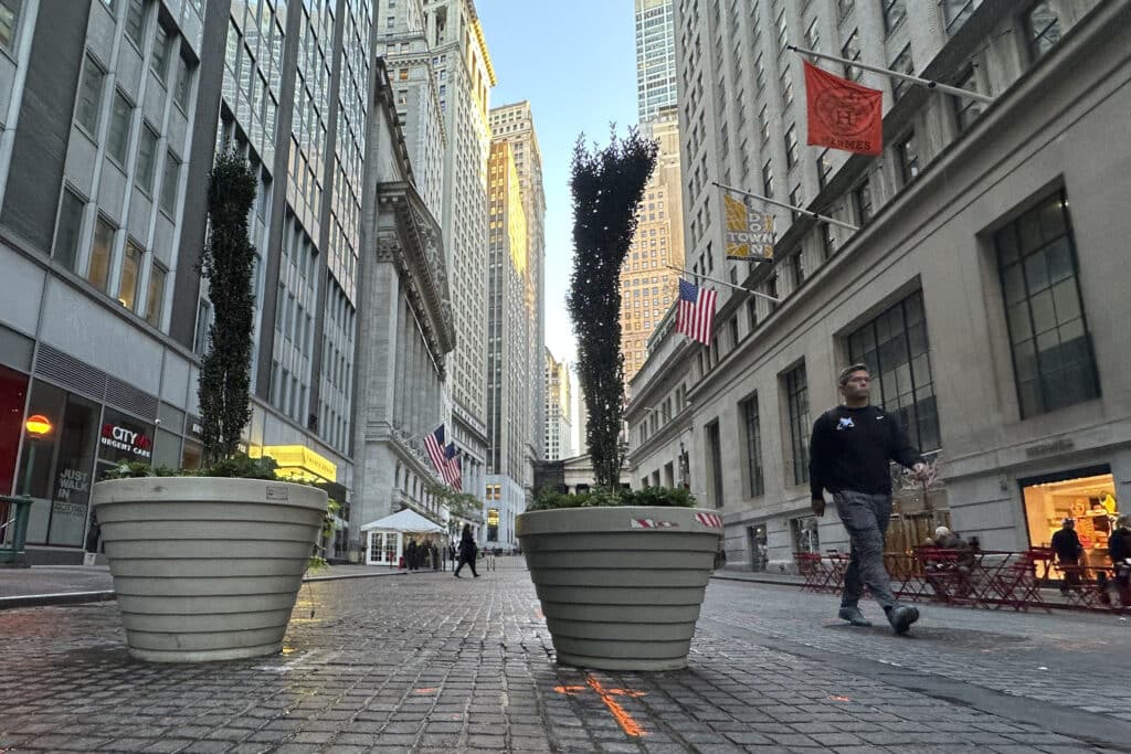 People pass the New York Stock Exchange, at rear, in New York's Financial District on Oct. 16, 2024. 