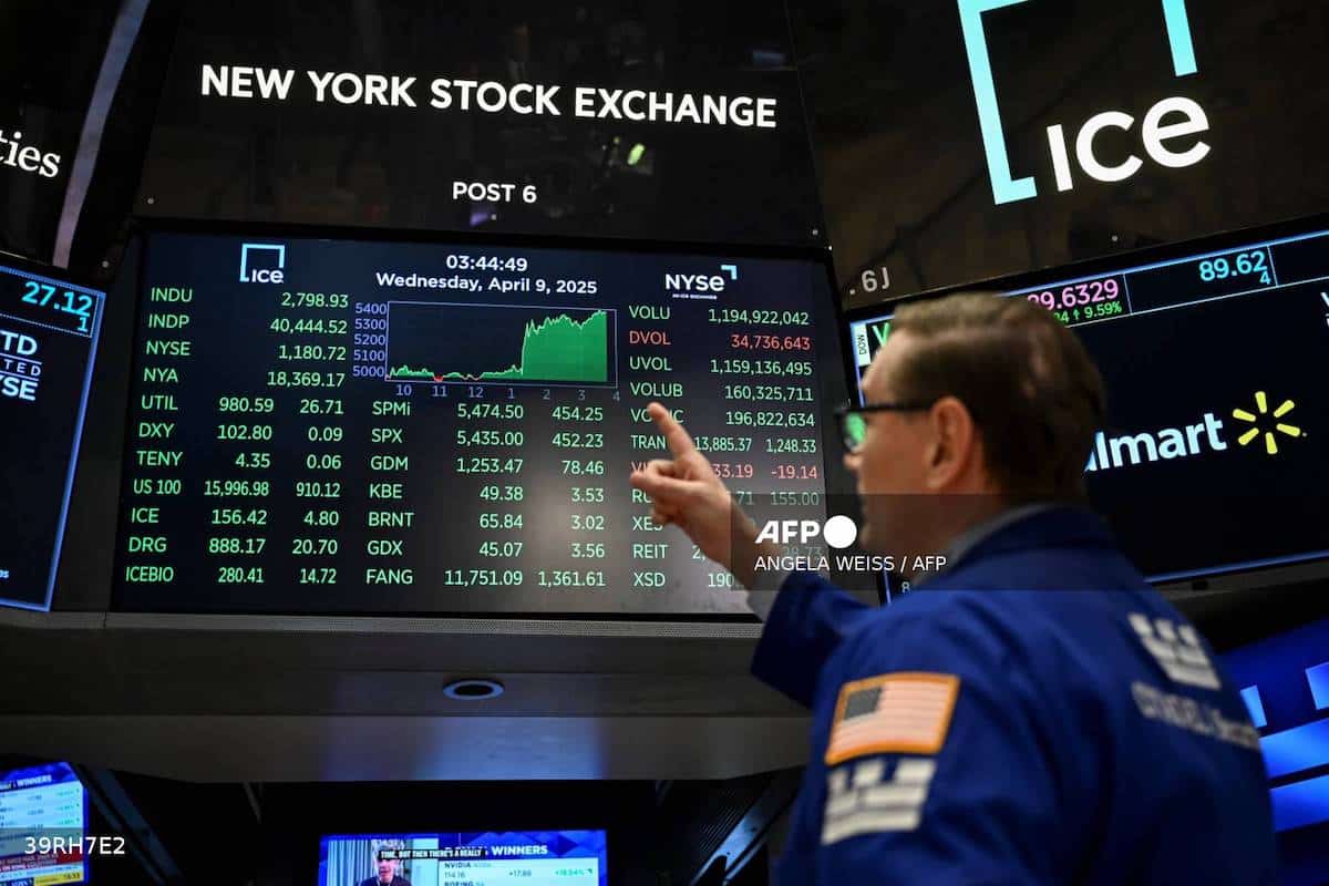 A trader points at stock data on a monitor at the floor of the New York Stock Exchange