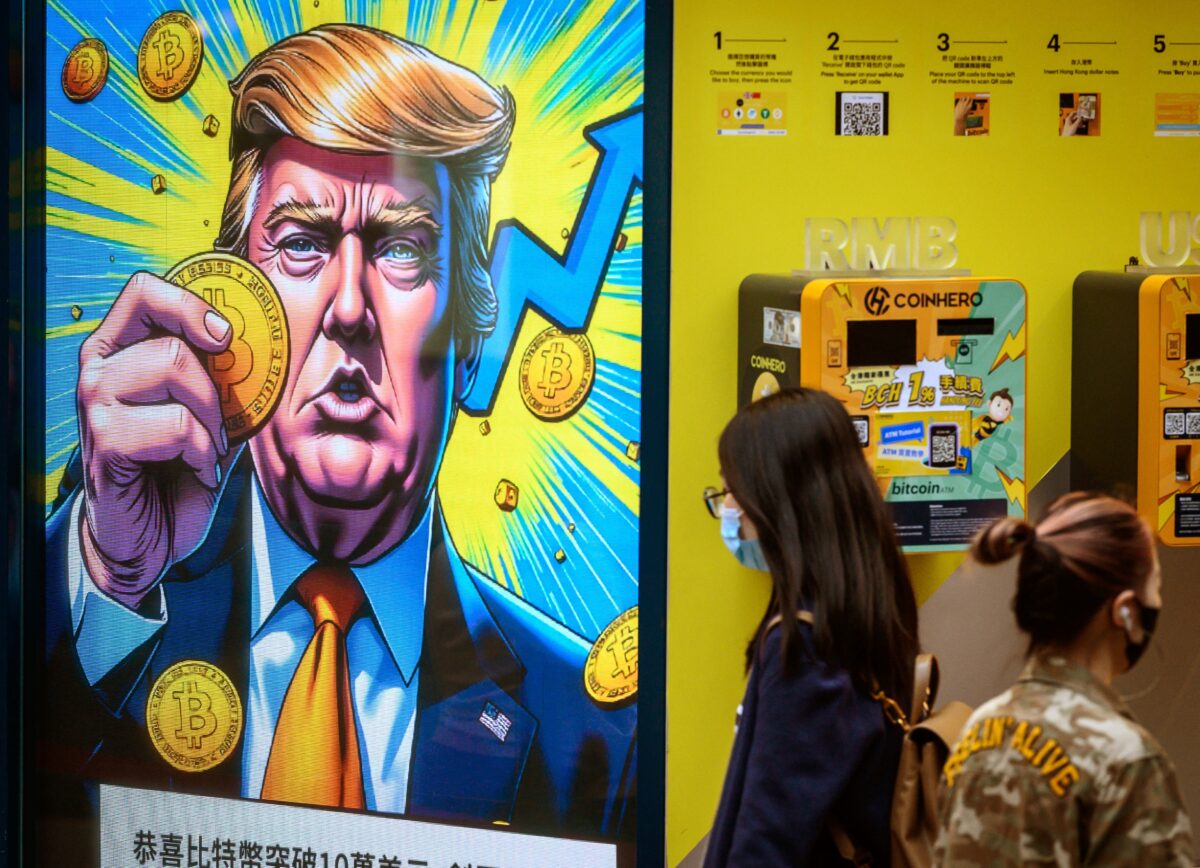 People walk past a cryptocurrency exchange office with a screen featuring US President Donald Trump holding cryptocurrency coins. (Photo by Mladen ANTONOV / AFP)