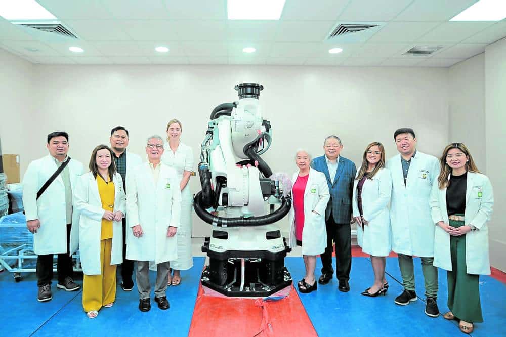 Hospital officials pose beside a surgical machine
