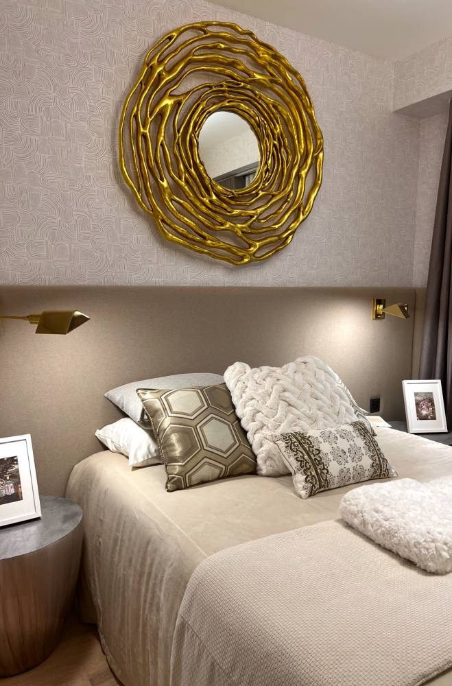A neutral bedroom with a gold accent mirror gives a luxurious
approach.